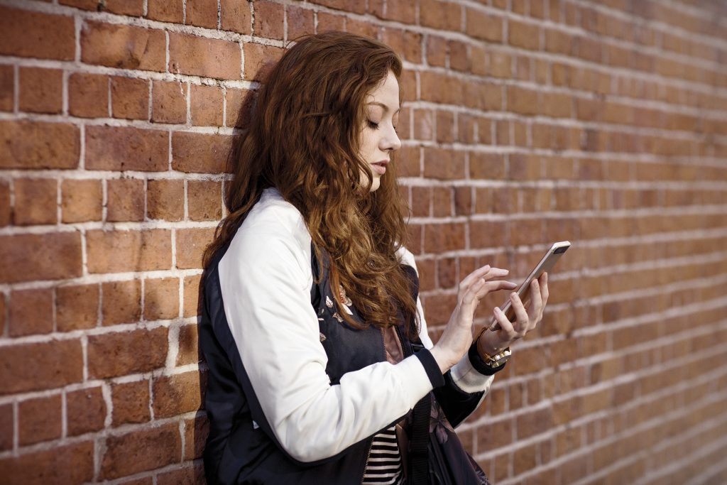 Woman on phone outdoors by a brick wall